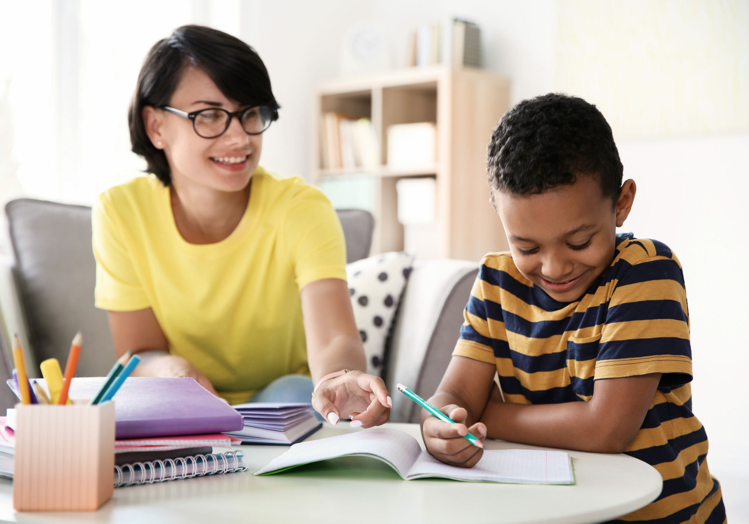 Young woman helping her child with homework at home. Elementary school